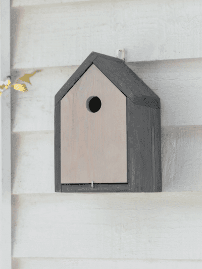 Garden Trading Traditional Bird House on a white shiplap wall in a garden