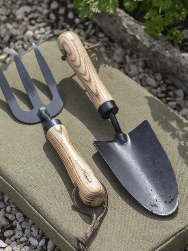 Gardening tools - a fork and trowel set on a kneeling pad