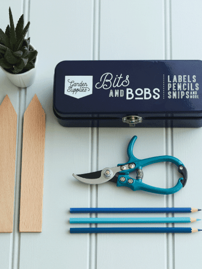 Burgon & Ball Store Tin Blue next to gardening tools and plant