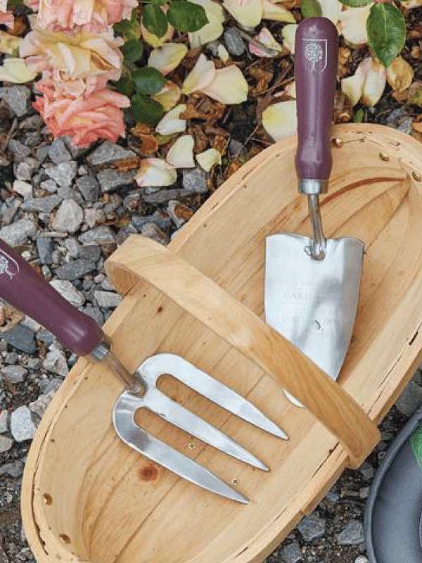 Burgon & Ball Trowel and fork set passiflora in a wicker basket in a garden setting