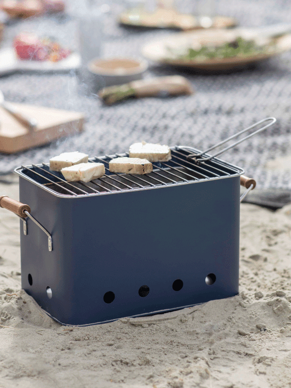 Blue square bucket BBQ on the beach with food grilling