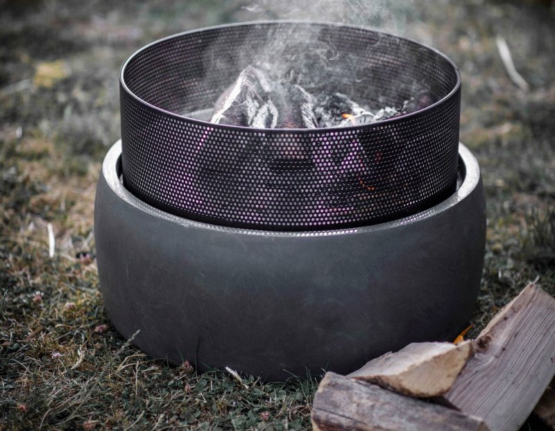 A round garden fire pit with a small pile of logs next to it