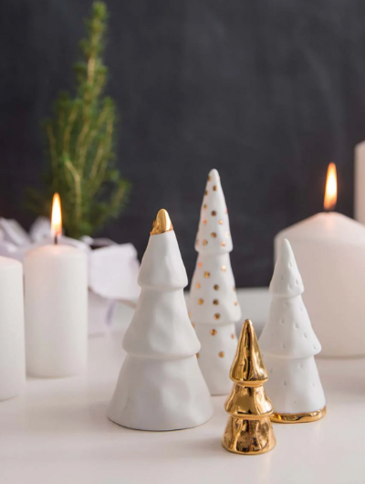 Räder Winter Forest Porcelain Fir Trees, set of four elegant white porcelain trees with delicate gold accents. Each tree features a unique design — gold base, gold tip, gold dots, and full gold tree — creating a sophisticated winter display. Perfect for Christmas villages, festive centrepieces, or minimalist shelf décor. The porcelain has a soft snow-like finish, adding a serene seasonal charm