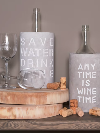 Concrete wine cooler by Räder Design embossed with “Anytime Is Wine Time,” perfect for wine lovers and stylish home décor.