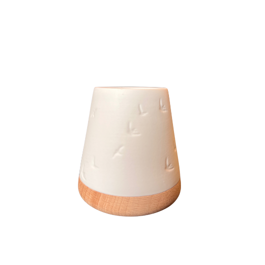 White unglazed porcelain tealight holder with embossed birds on an oiled wooden base by Räder, casting a warm glow when lit.