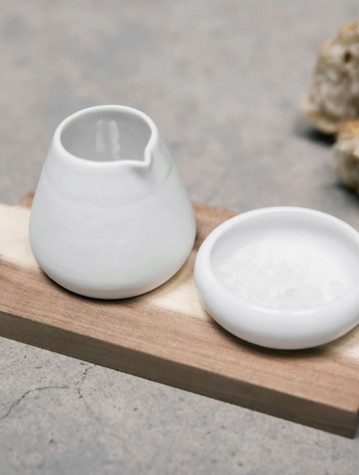 Oil and salt pots with acacia wood tray by Räder Designs, porcelain vessels by Indigo Ruh, versatile for oils, spices, or condiments.