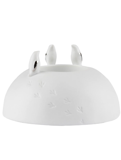 Räder porcelain tealight holder with silver-winged penguins and embossed snowy footprints, Dia 10cm x H6cm, glowing softly when lit.