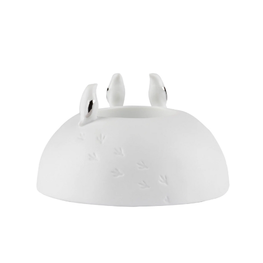 Räder porcelain tealight holder with silver-winged penguins and embossed snowy footprints, Dia 10cm x H6cm, glowing softly when lit.