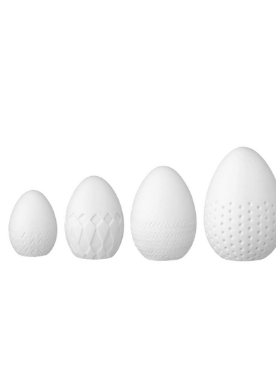 Set of four white porcelain eggs by Räder Design with unique embossed patterns, handmade and varying in size for decorative display.