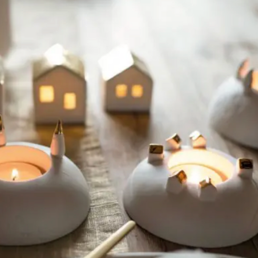 Räder porcelain tealight holder with silver-winged penguins and embossed snowy footprints, Dia 10cm x H6cm, glowing softly when lit.