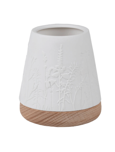 White unglazed porcelain tealight holder with embossed flowers on an oiled wooden base by Räder, casting a warm glow when lit.