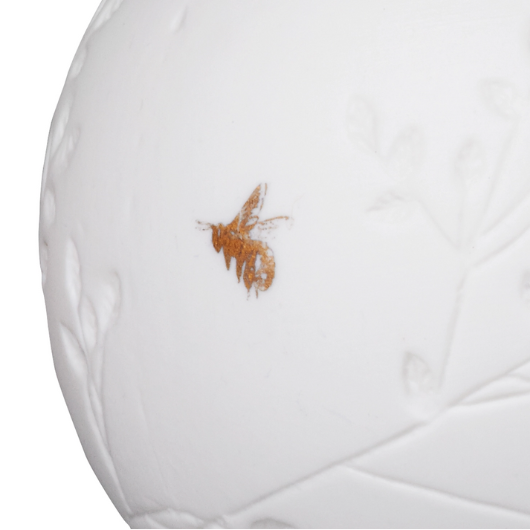 Räder white porcelain tea light holder with golden bird, embossed flowers, and gold-painted bee, 7cm diameter × 7cm high, matte exterior.