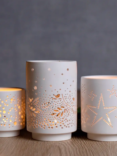 Set of three white porcelain tea light holders by Räder Design with openwork patterns in dots, stars, and birds & leaves, matte finish.