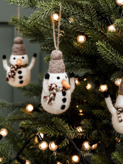 Three hand-felted Southwold Christmas Snowmen with scarves, hats, carrot noses, and coal buttons, hanging on a Christmas tree.