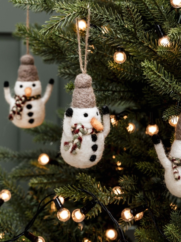 Three hand-felted Southwold Christmas Snowmen with scarves, hats, carrot noses, and coal buttons, hanging on a Christmas tree.