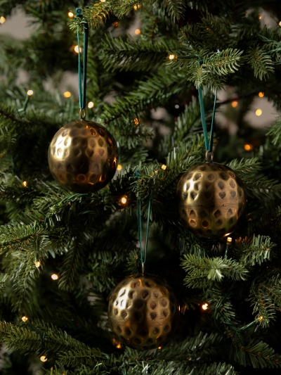 Set of three Ardington Hammered Baubles in antique brass with dark green velvet ribbons, perfect for a traditional red, green, and gold Christmas tree.