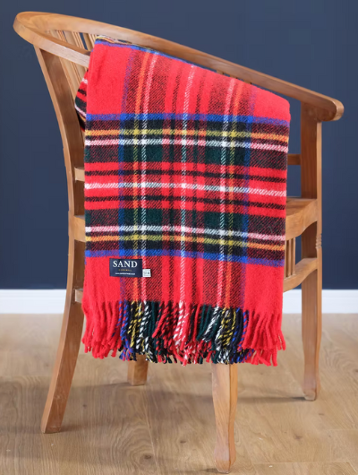 Royal Stewart tartan wool throw with red twisted tassels, draped over a sofa.