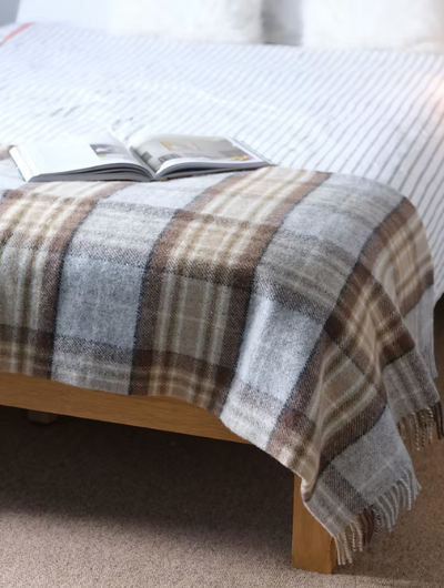 McKellar tartan wool Blanket throw with matching twisted tassels, draped over a sofa.