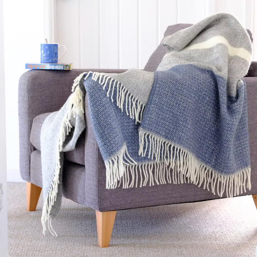 Slate Blue and Grey Wool Illusion Blanket Throw with cream tassels draped on sofa