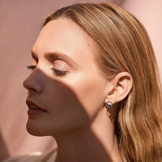 Model wearing Joma Jewellery February Birthstone amethyst stud earrings, symbolising calm and inner strength.