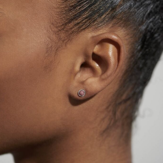 Close-up of Joma Jewellery October Birthstone Earrings with Tourmaline stones and traits card.