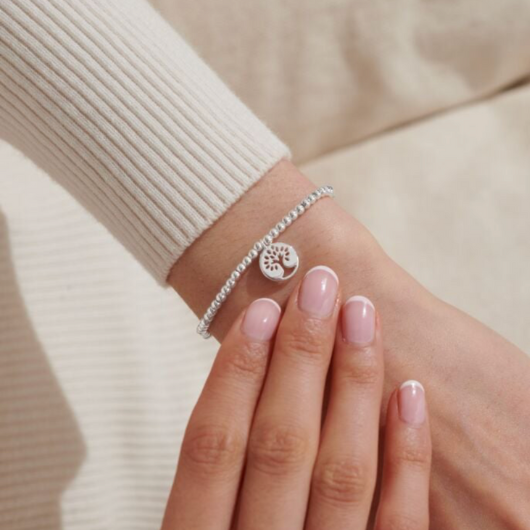 A Little Family Bracelet – silver-plated circular charm with cut-out tree design on stretch bracelet.