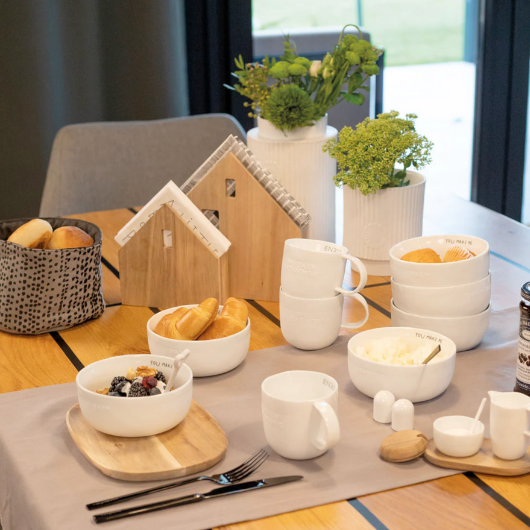 Village House Napkin Holder in acacia wood by Sarah Blienert, holding square dinner napkins.