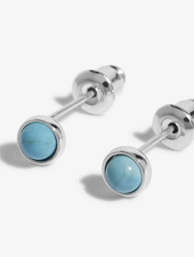 Close-up of Joma Jewellery December Birthstone Earrings with Turquoise stones and month traits card.