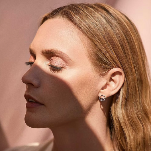 Model wearing Joma Jewellery January Birthstone silver-plated garnet halo stud earrings, symbolising love and strength.