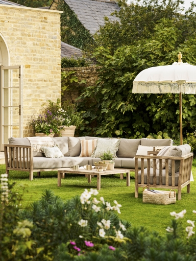 Garden Trading Porthallow Dark Natural acacia corner sofa set with matching armchair and coffee table on a garden patio.