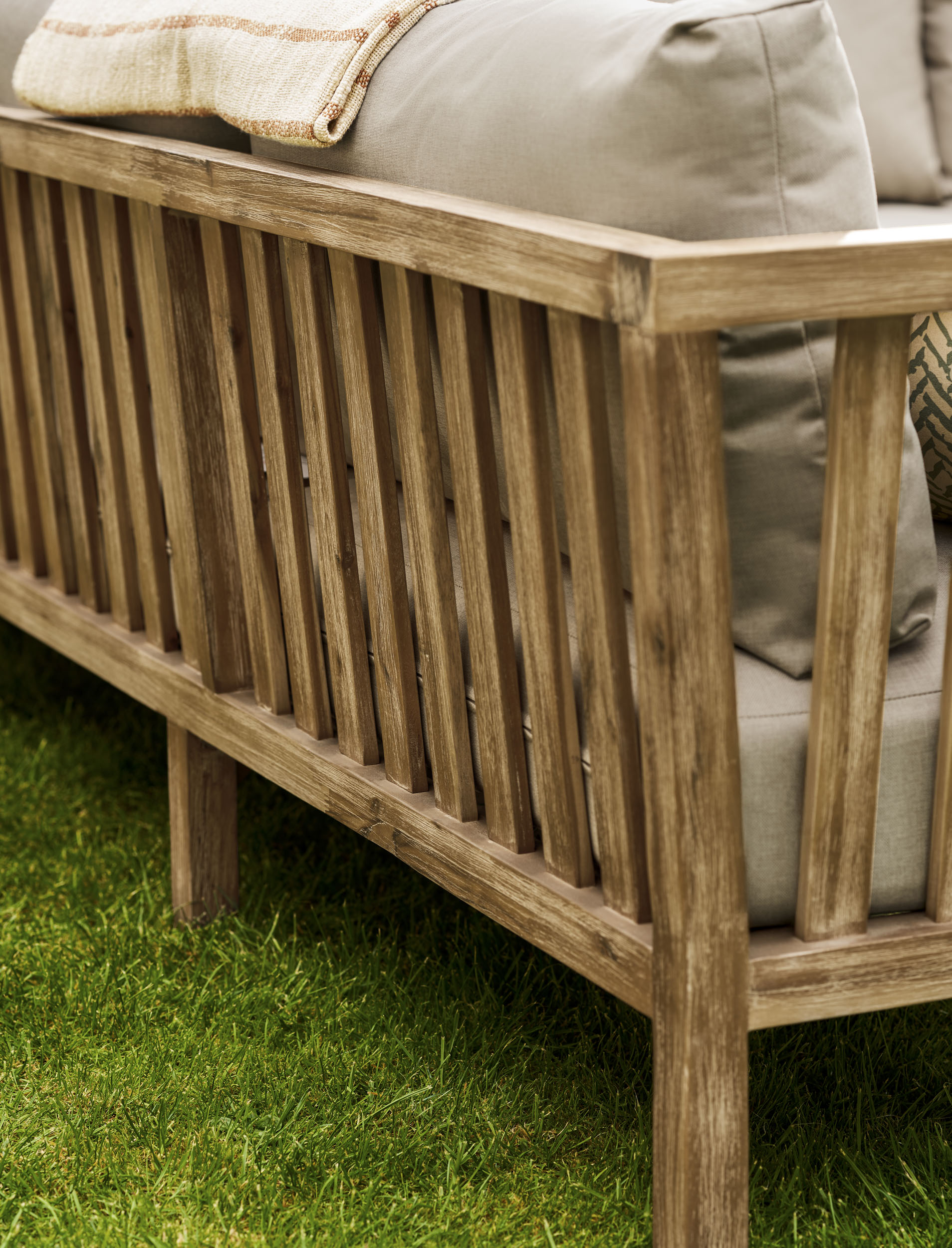 Garden Trading Porthallow Dark Natural acacia corner sofa set with matching armchair and coffee table on a garden patio. Sizes