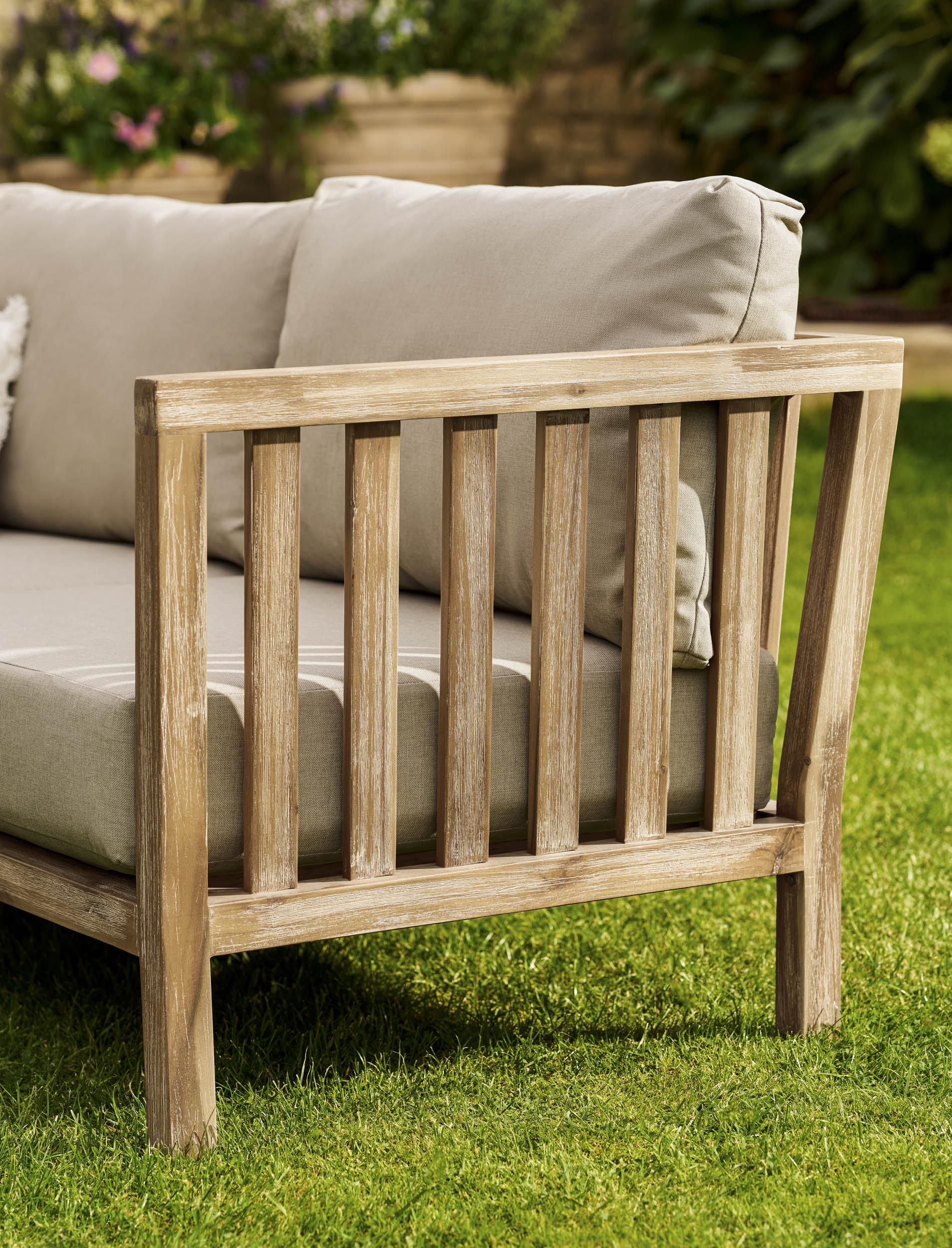 Garden Trading Porthallow Dark Natural acacia corner sofa set with matching armchair and coffee table on a garden patio. Sizes