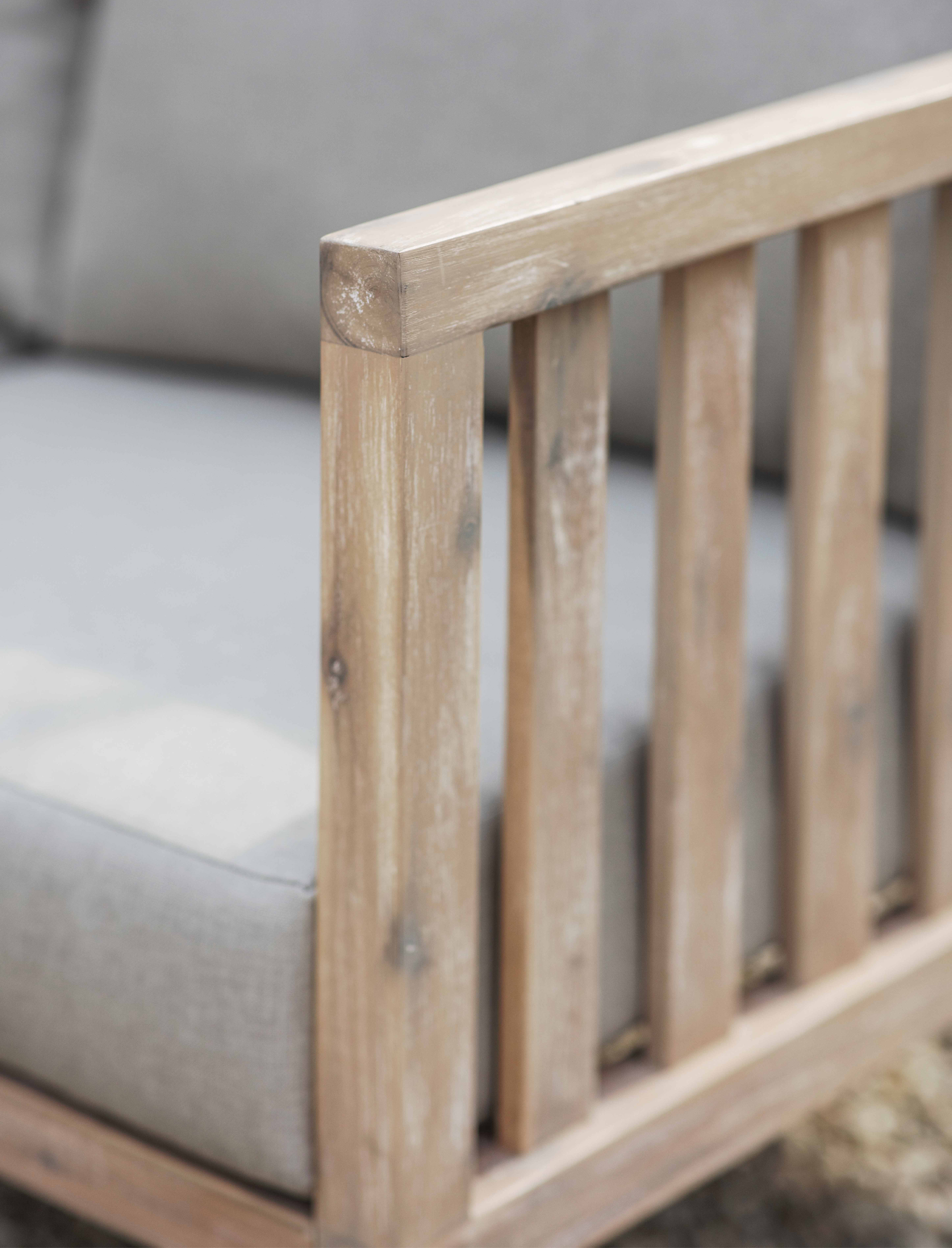 Garden Trading Porthallow 2 seater sofa in natural acacia wood with grey cushions styled on an outdoor patio.