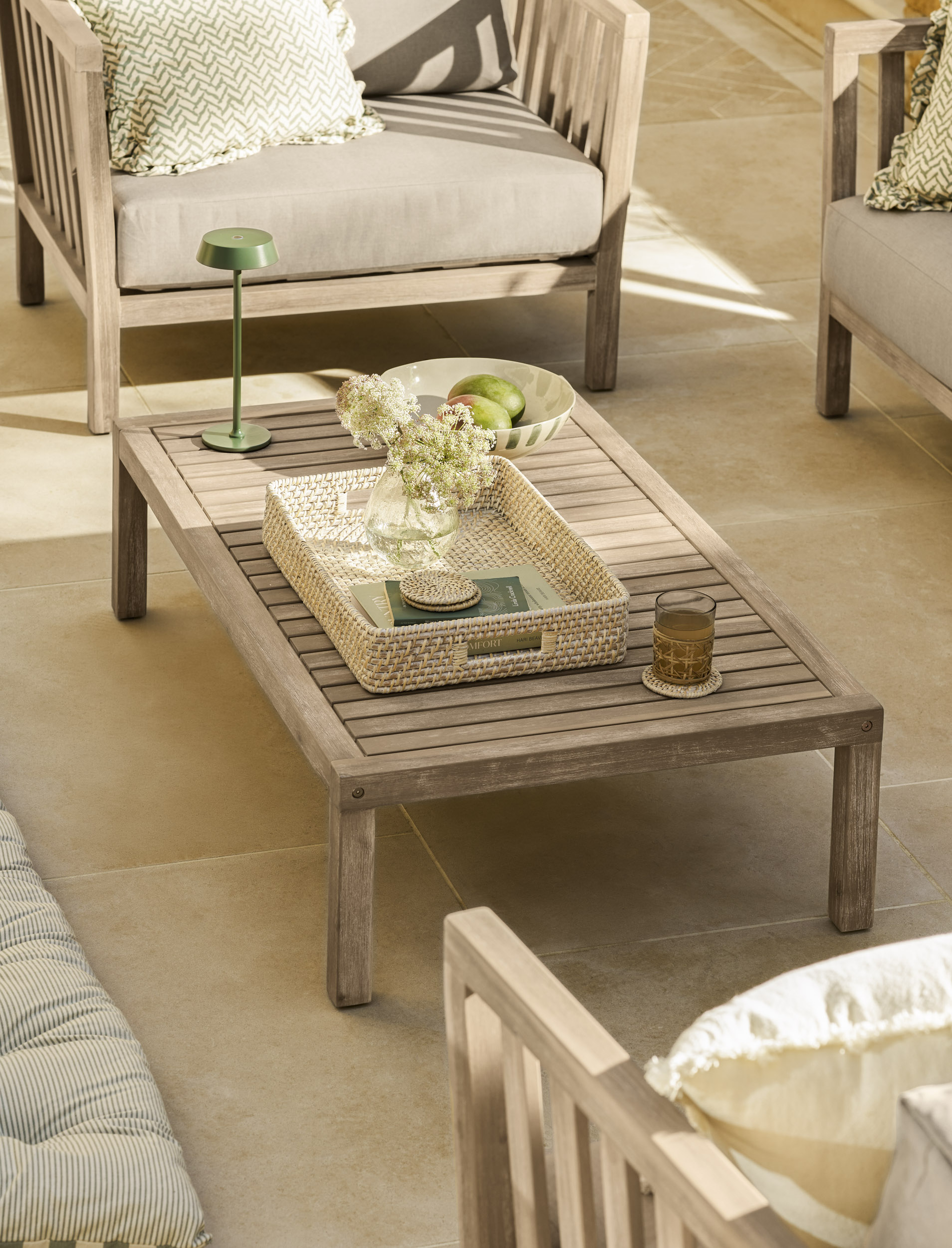 Garden Trading Porthallow 2 seater sofa set in natural acacia wood with matching armchairs and coffee table outdoors.