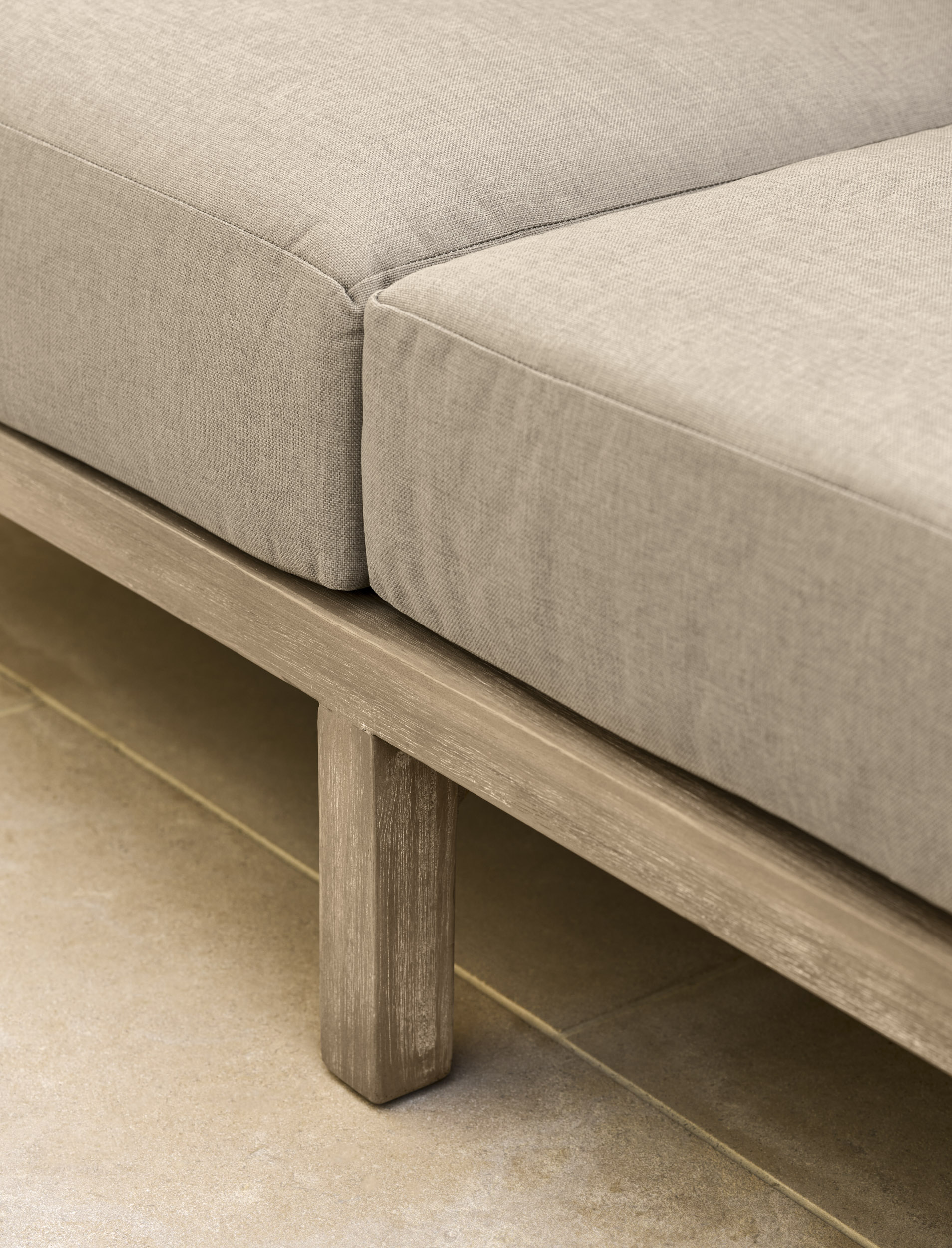 Garden Trading Porthallow 2 seater sofa set in natural acacia wood with matching armchairs and coffee table outdoors.