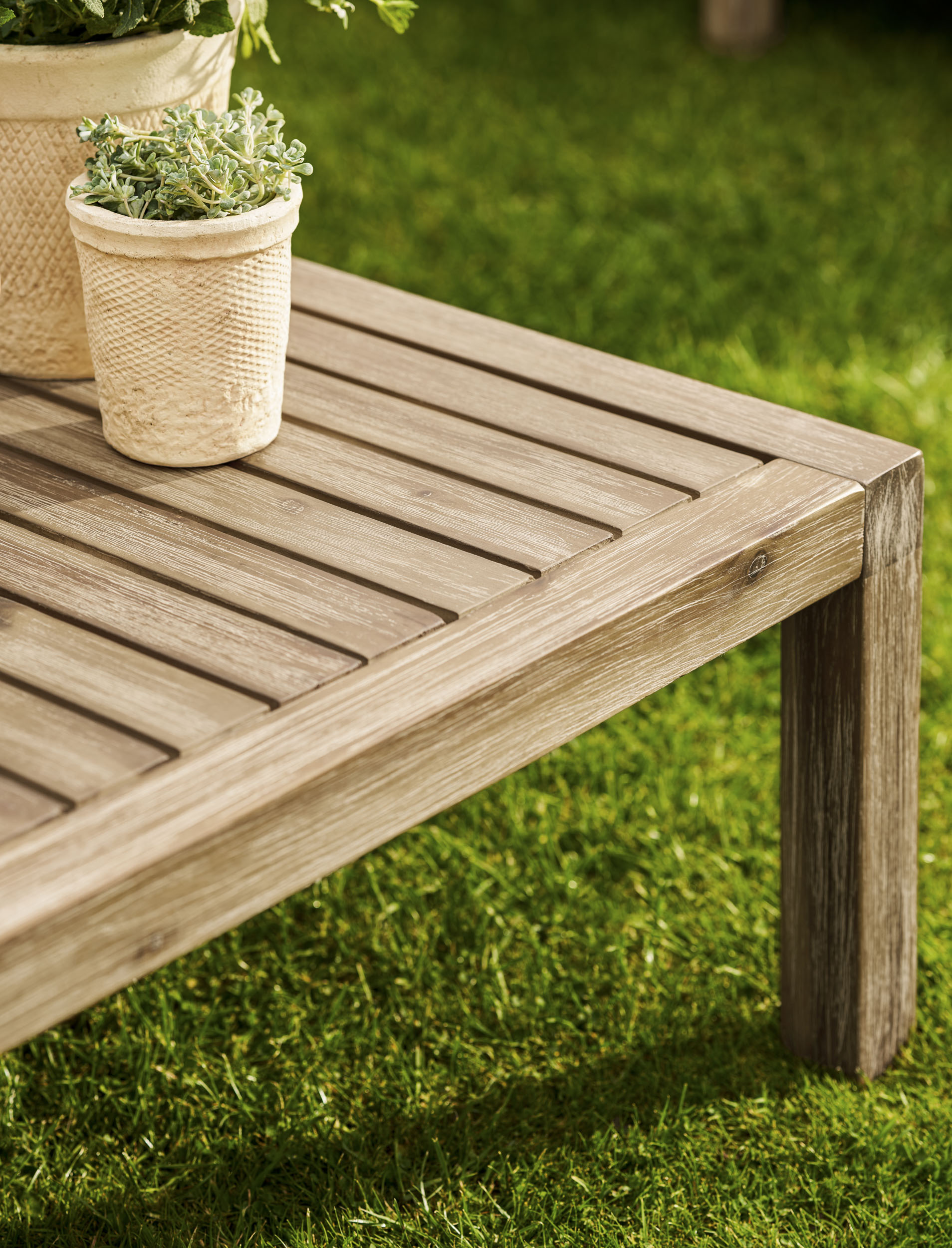 Garden Trading Porthallow Dark Natural acacia corner sofa set with matching armchair and coffee table on a garden patio. Sizes